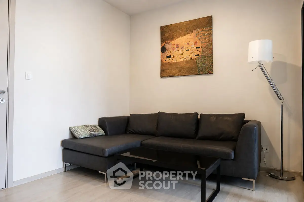 Modern living room with stylish black sofa and contemporary art on the wall.