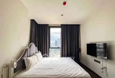 Modern bedroom with city view and wall-mounted TV in high-rise apartment.