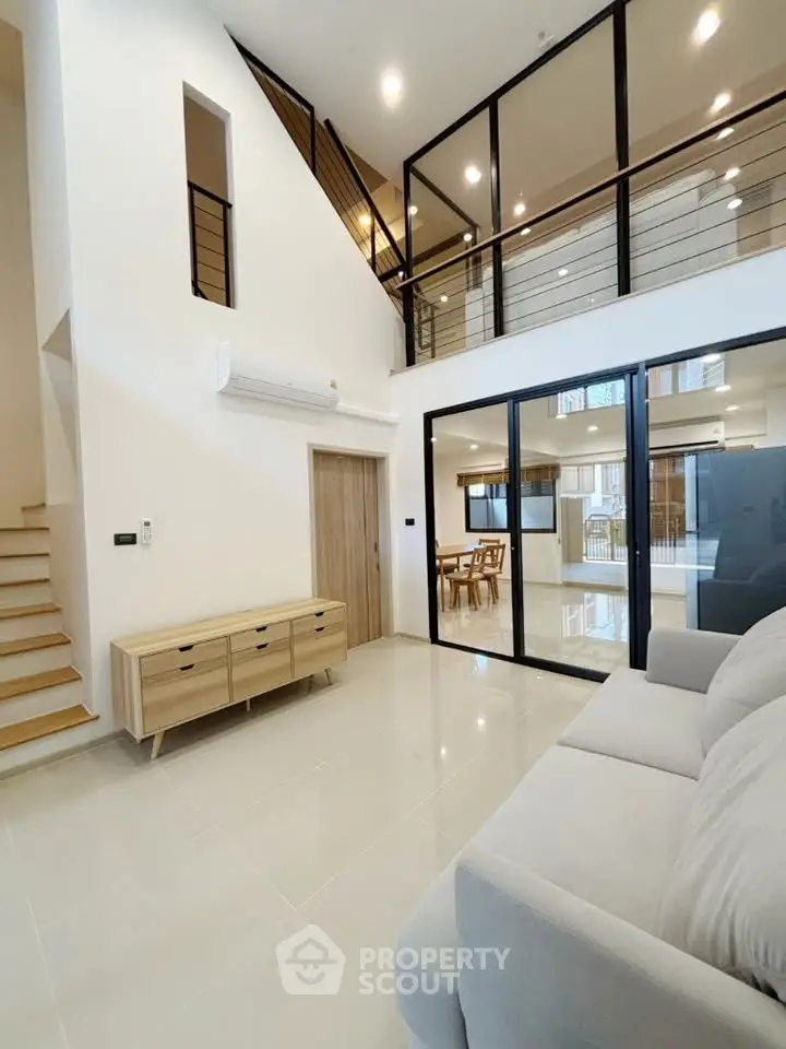 Spacious modern living room with high ceilings and elegant glass railing