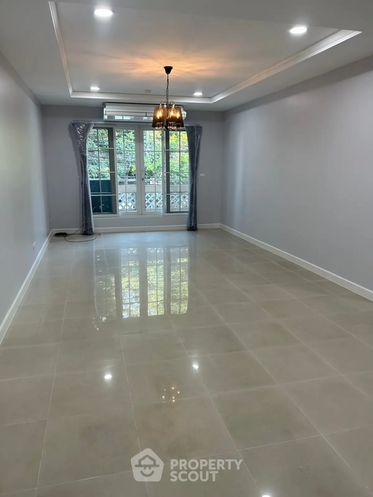 Spacious unfurnished living room with large windows and elegant chandelier