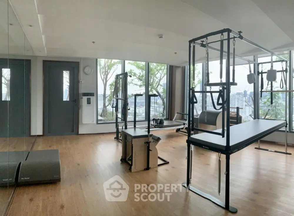 Modern gym with city view, featuring Pilates equipment and large windows for natural light.