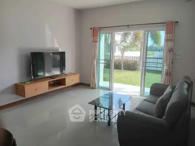 Modern living room with sleek furniture and garden view through sliding glass doors.