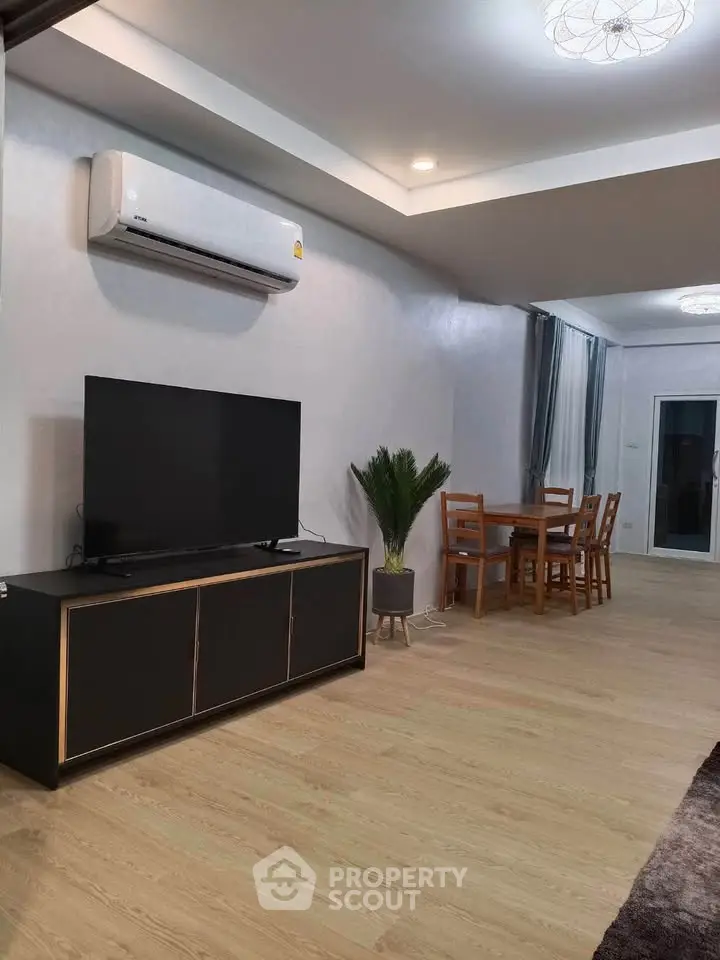 Modern living room with sleek TV unit and dining area, featuring stylish wooden flooring.