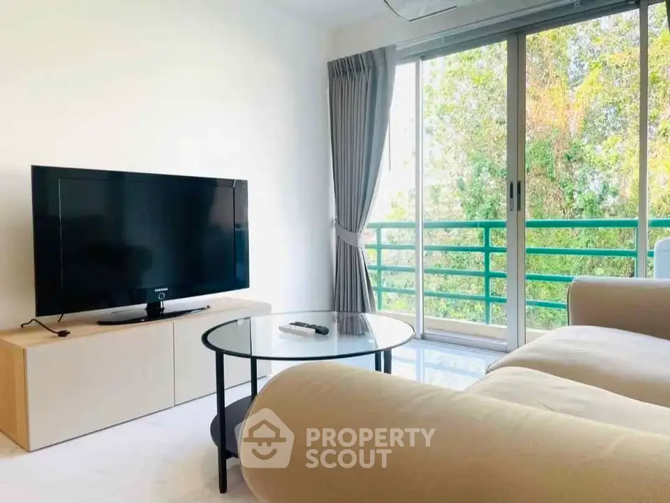 Bright living room with large TV, cozy sofa, and balcony view.