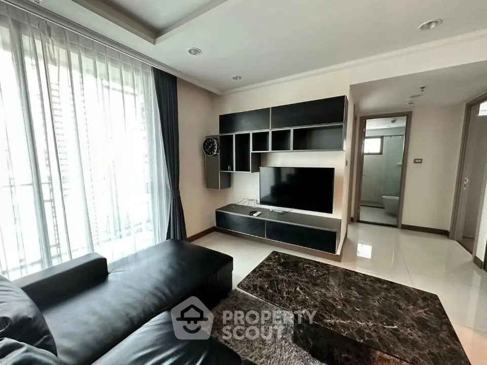 Modern living room with sleek black furniture and wall-mounted TV in a stylish apartment.