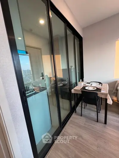 Modern apartment with glass sliding doors and cozy dining area, featuring a sleek interior design.