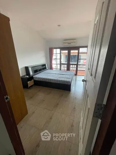 Cozy bedroom with wooden flooring and balcony access