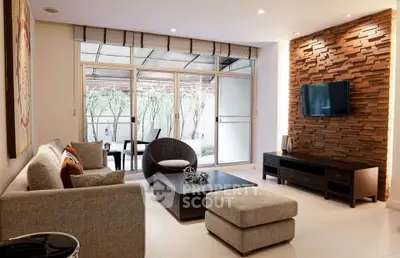 Modern living room with stylish decor and large windows opening to a patio, featuring a cozy seating area.