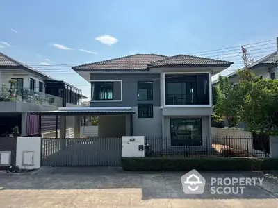 Modern two-story house with sleek design and spacious driveway in a suburban neighborhood.