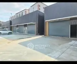 Modern commercial building with large garage doors and ample parking space.