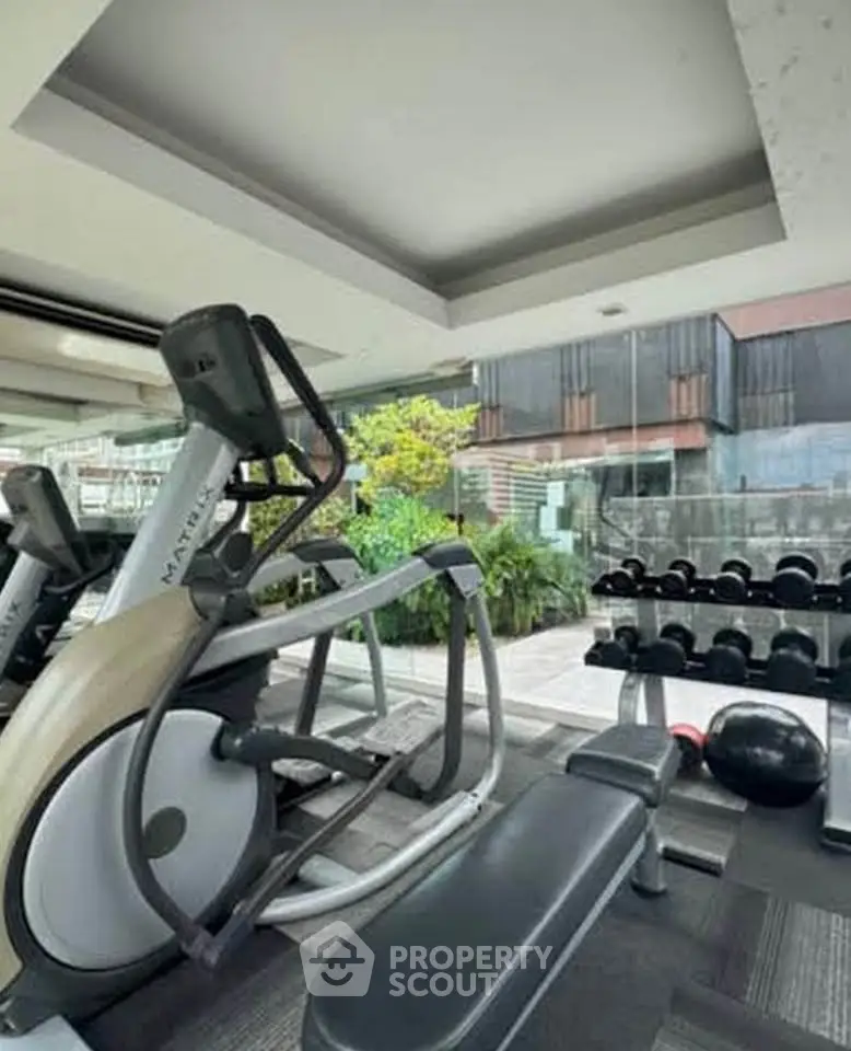 Modern gym with state-of-the-art equipment and large windows offering natural light.
