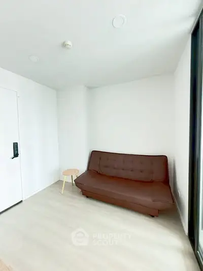 Minimalist living room with brown sofa and side table, bright natural light.