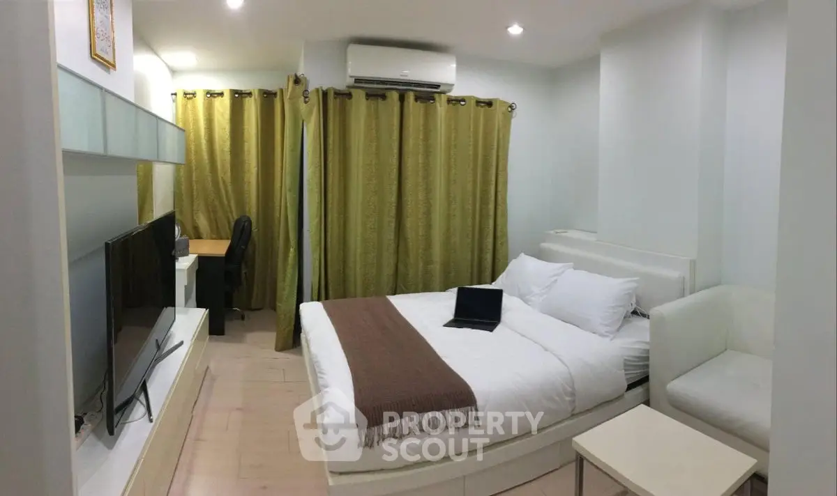 Cozy bedroom with modern decor, featuring a comfortable bed, TV, and workspace, ideal for relaxation and productivity.