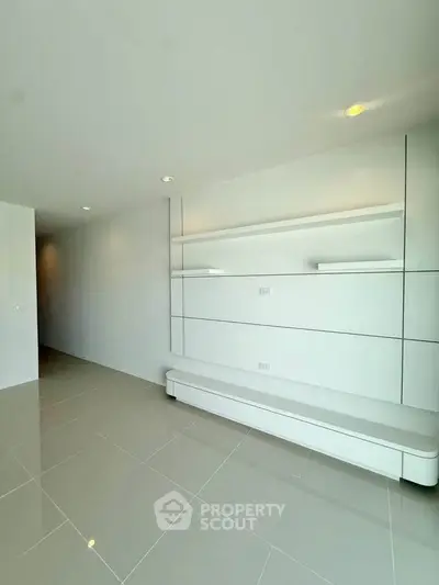 Modern minimalist living room with sleek built-in shelving and glossy tiled flooring.