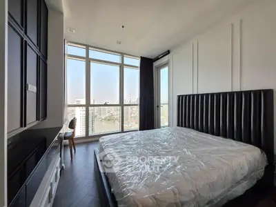 Spacious bedroom with floor-to-ceiling windows offering stunning city views.