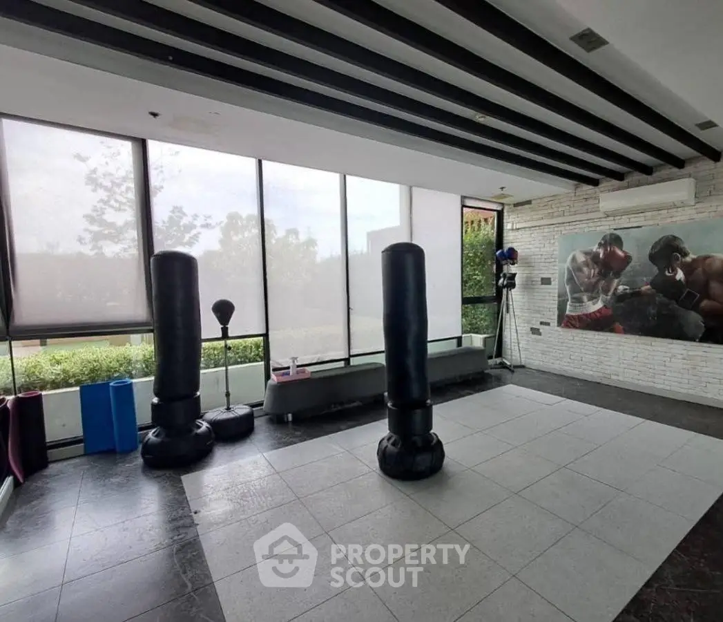 Spacious home gym with punching bags and large windows for natural light.