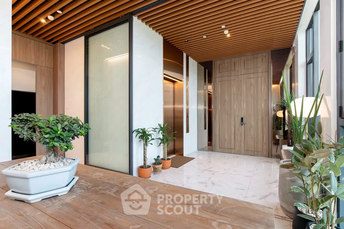 Luxurious modern building entrance with elegant wood paneling and marble flooring, featuring stylish potted plants.