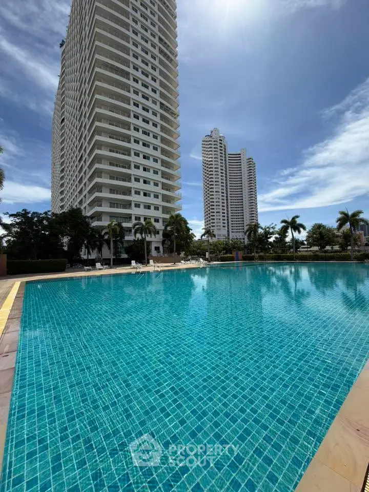 Luxurious high-rise condos with a stunning pool and palm-lined surroundings, perfect for upscale living.