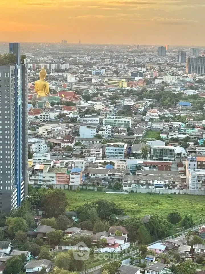 Stunning cityscape view with golden Buddha statue at sunset, showcasing urban and cultural harmony.