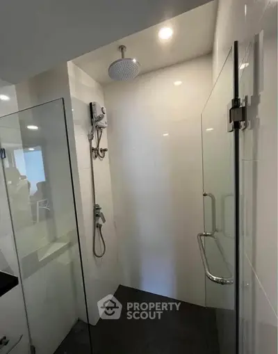 Modern bathroom with sleek glass shower enclosure and rainfall showerhead.