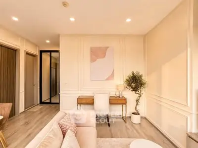 Elegant living room with modern decor and natural light, featuring a cozy seating area and stylish desk.