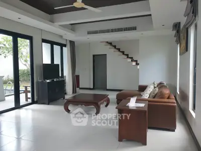 Spacious living room with modern furniture and pool view, perfect for relaxation and entertainment.