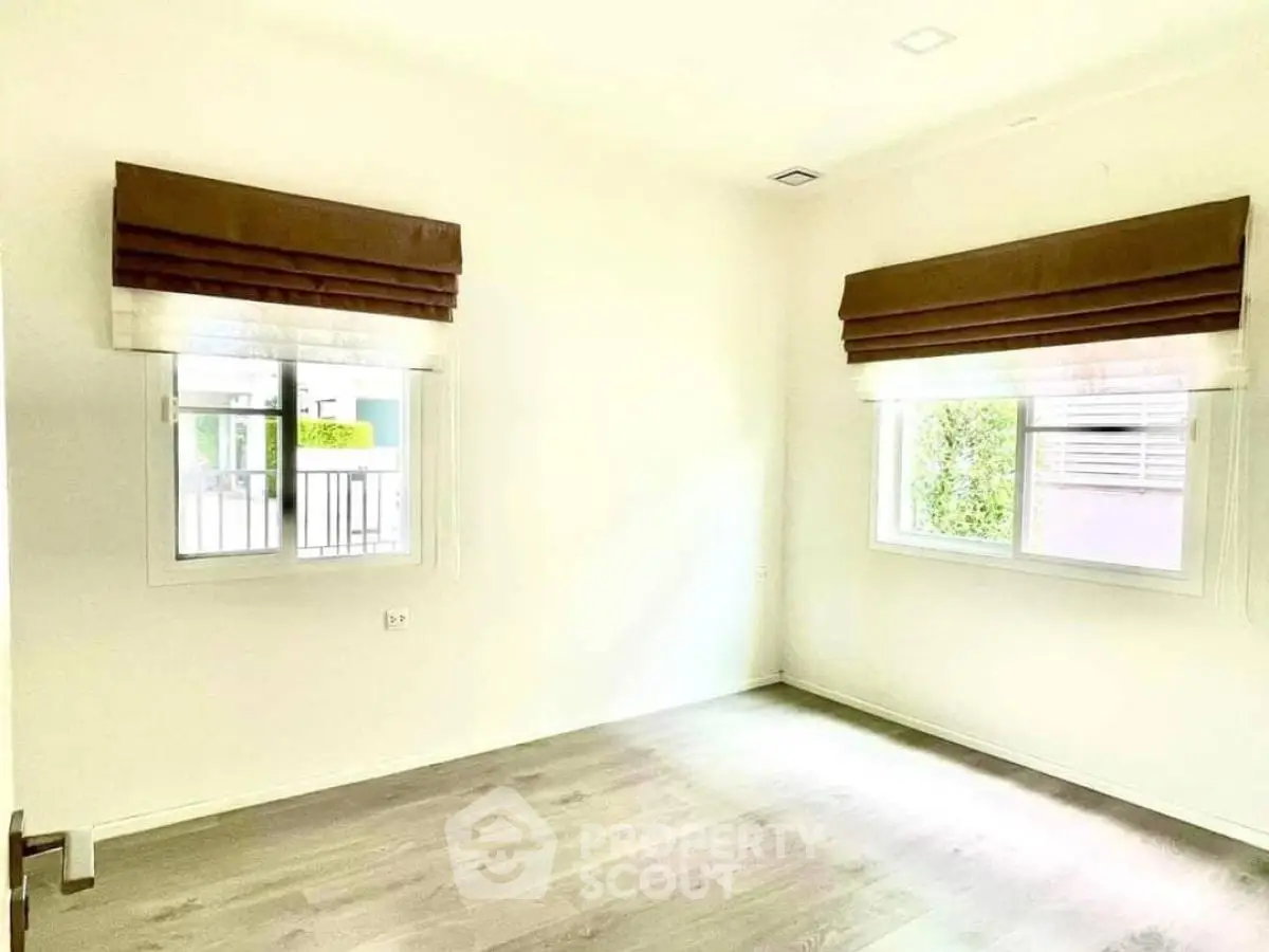 Bright empty room with large windows and wooden flooring