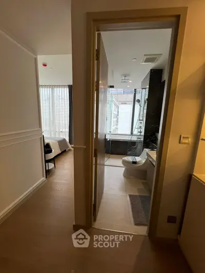 Modern apartment interior with bedroom and bathroom, featuring sleek design and natural light.