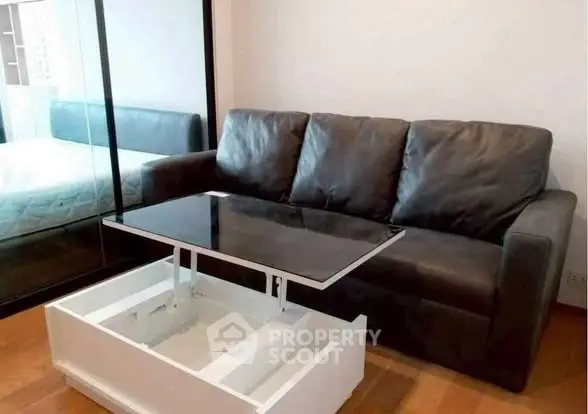 Modern living room with sleek black sofa and innovative lift-top coffee table.