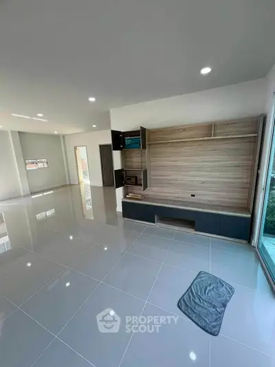 Spacious modern living room with sleek tile flooring and built-in wooden entertainment unit.