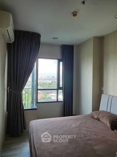 Cozy bedroom with large window offering stunning city view, perfect for relaxation and comfort.