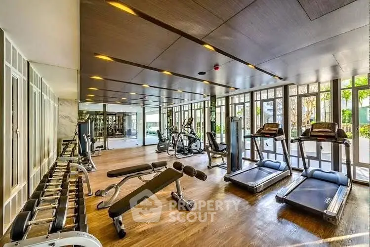 Luxurious gym with state-of-the-art equipment and floor-to-ceiling windows in modern building.