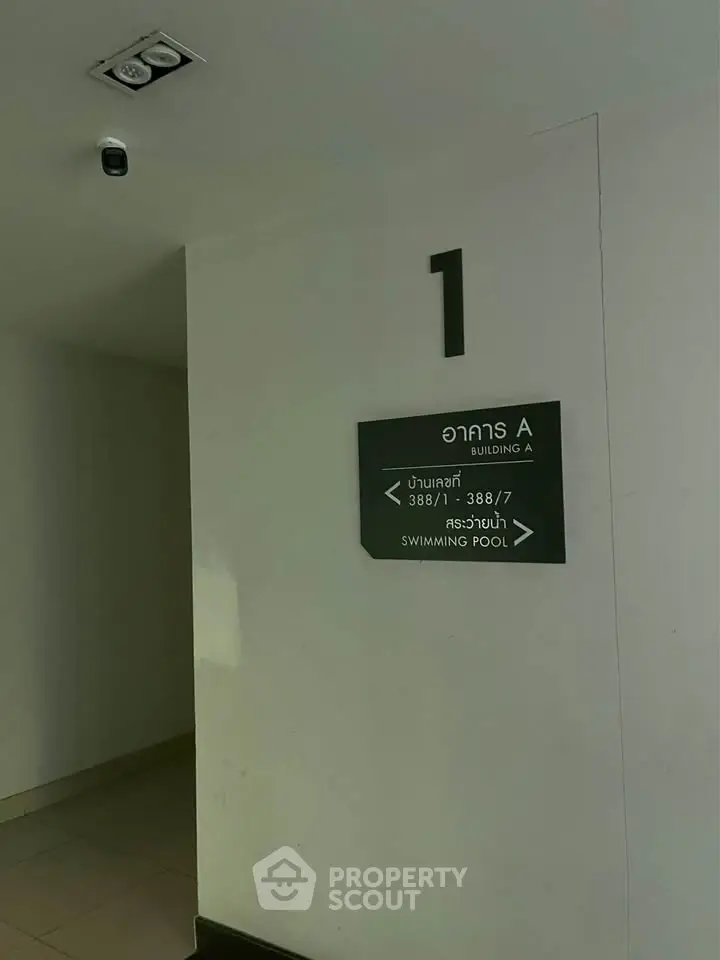 Building corridor with directional sign to swimming pool and unit numbers.