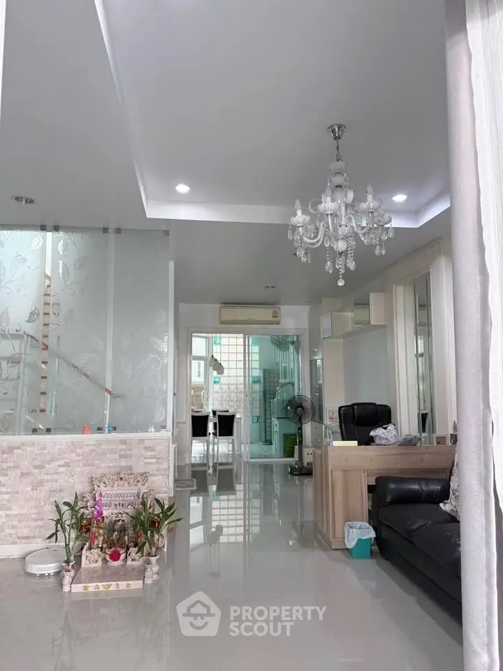 Elegant living room with chandelier and modern decor, featuring a sleek open layout and stylish furnishings.