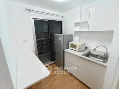 Modern kitchen with sleek appliances and balcony access, featuring a compact design and efficient layout.