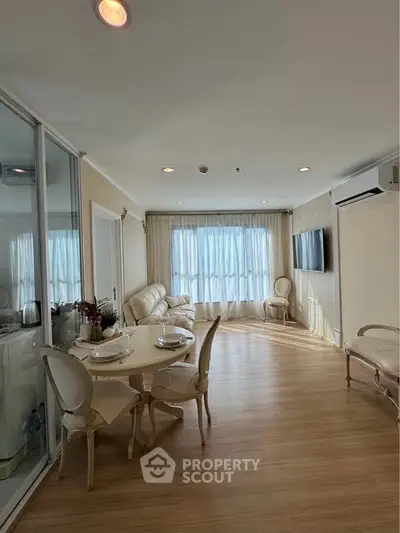 Elegant living room with natural light, stylish furniture, and wooden flooring in a modern apartment.
