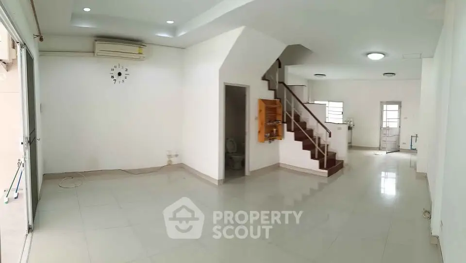 Spacious open-plan living area with staircase and modern tiled flooring