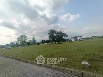 Expansive plot of land with lush greenery and distant house, perfect for development.
