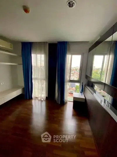 Spacious living room with large windows and wooden flooring, offering a bright and airy ambiance.