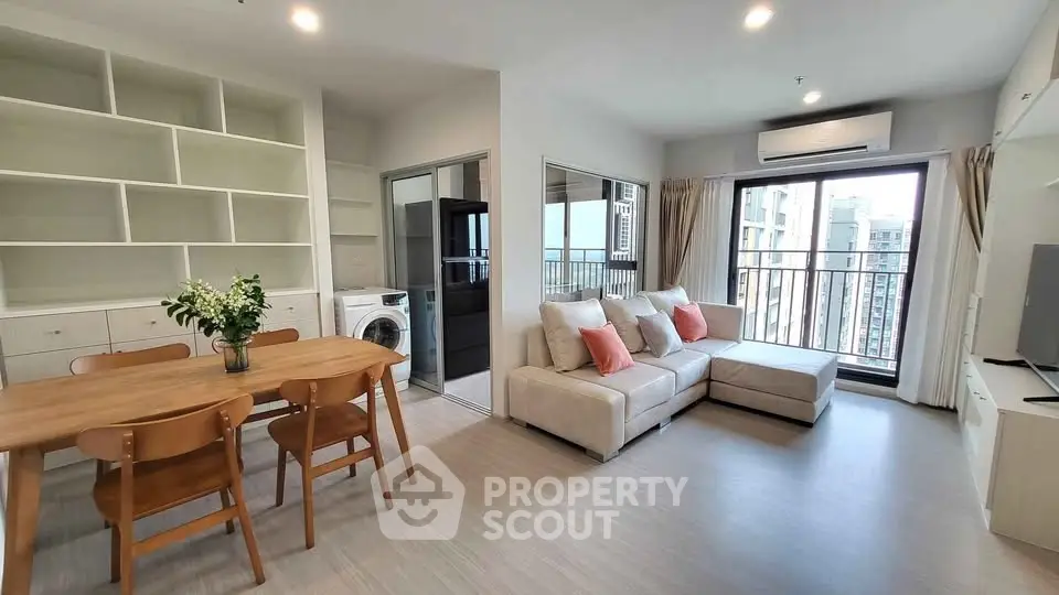 Modern living room with open layout, featuring a cozy sofa, dining area, and balcony view.