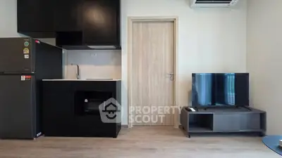 Modern apartment interior with sleek kitchen and cozy living area featuring a flat-screen TV.