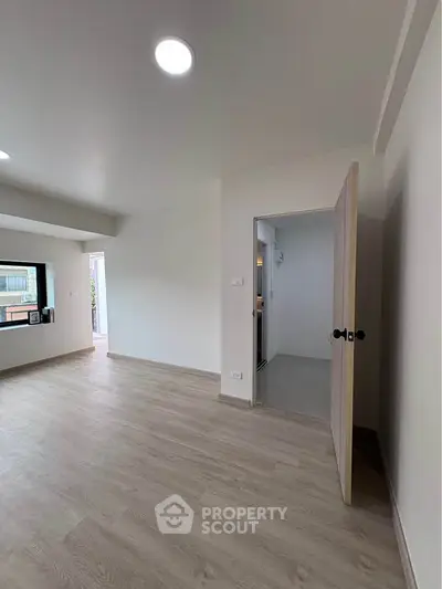 Spacious modern living room with wooden flooring and open doorway to kitchen area.