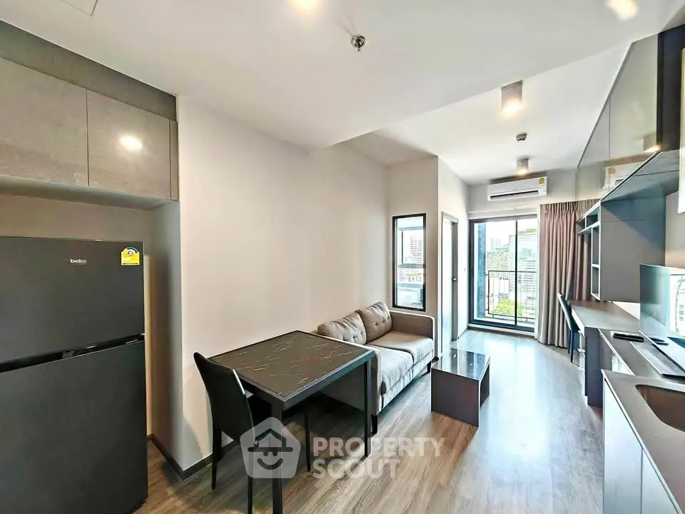Modern apartment interior with open kitchen and cozy living area, featuring sleek furniture and city view balcony.