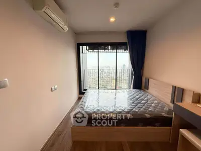 Modern bedroom with city view and balcony access in high-rise apartment.