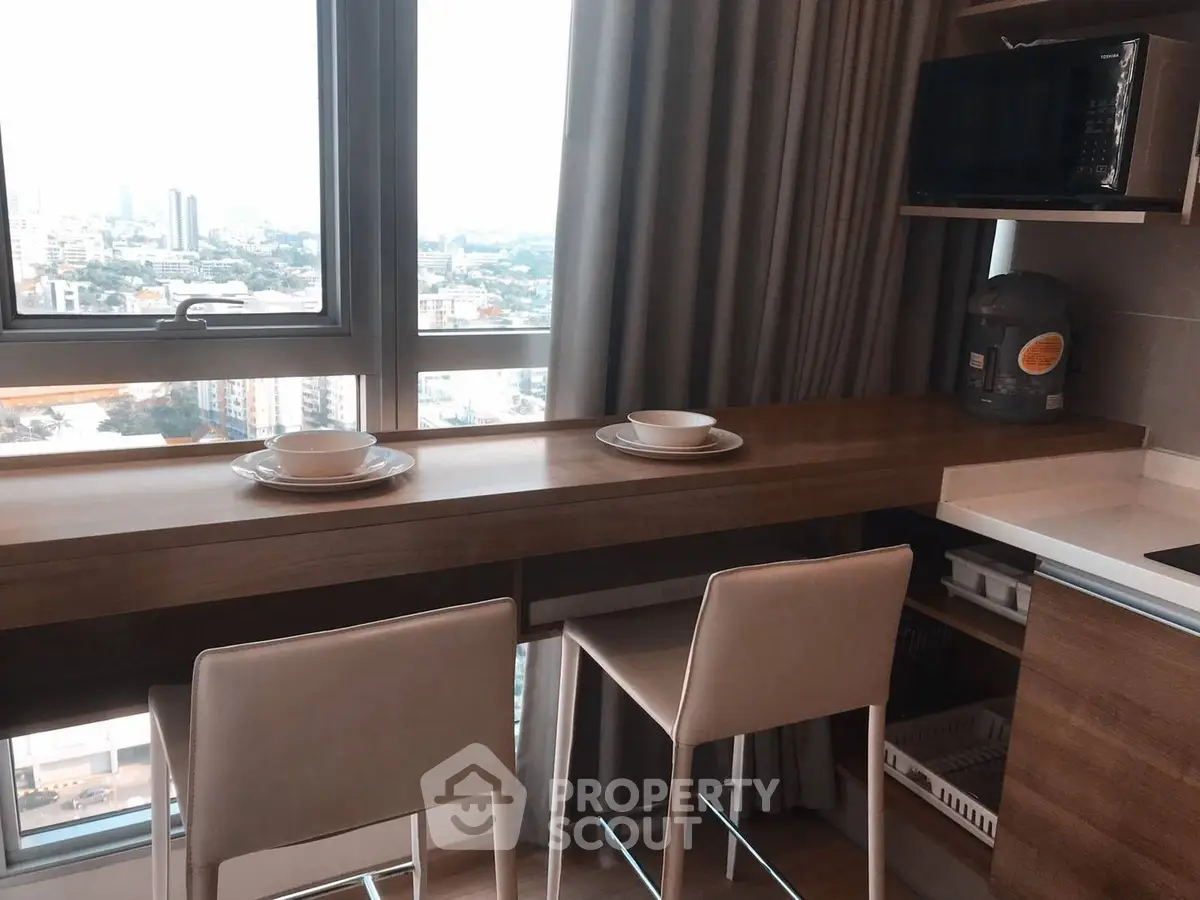 Modern kitchen with city view, featuring a breakfast bar and sleek appliances.