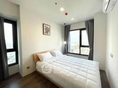 Bright and modern bedroom with large windows and city view, featuring minimalist decor and cozy bedding.