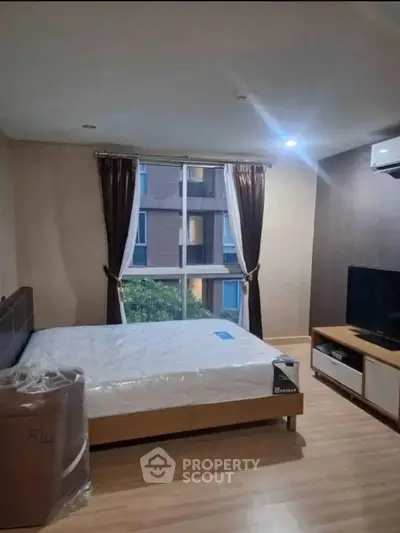 Modern bedroom with large window and stylish furnishings in a contemporary apartment.