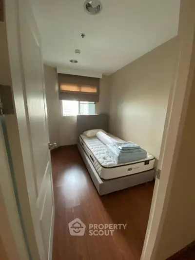 Cozy small bedroom with single bed and wooden flooring, perfect for minimalist living.