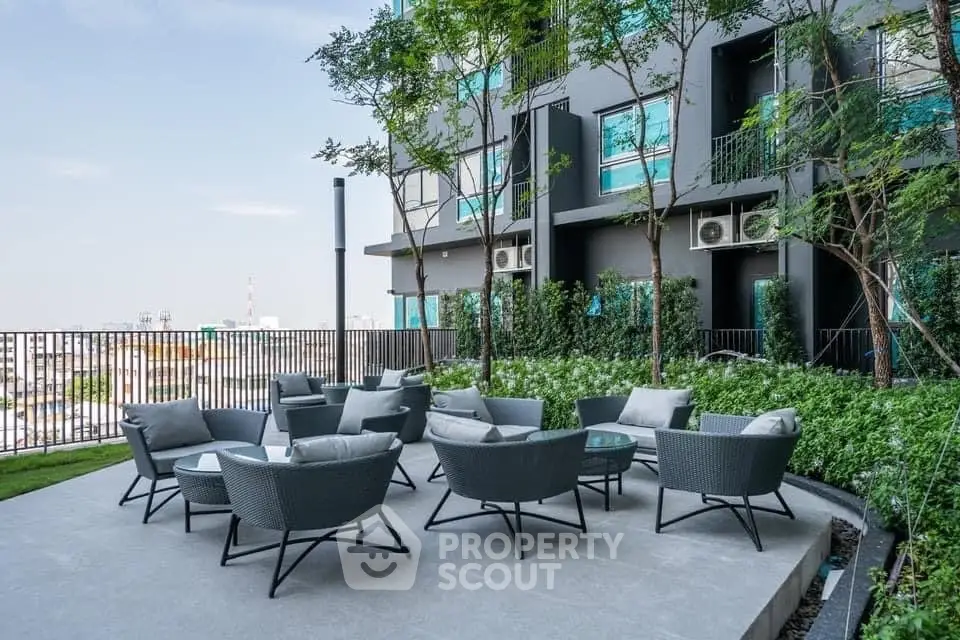 Luxurious outdoor seating area with modern chairs and lush greenery in a high-rise building.