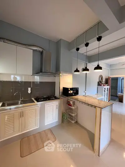 Modern kitchen with sleek design, featuring gas stove and stylish lighting, perfect for culinary enthusiasts.